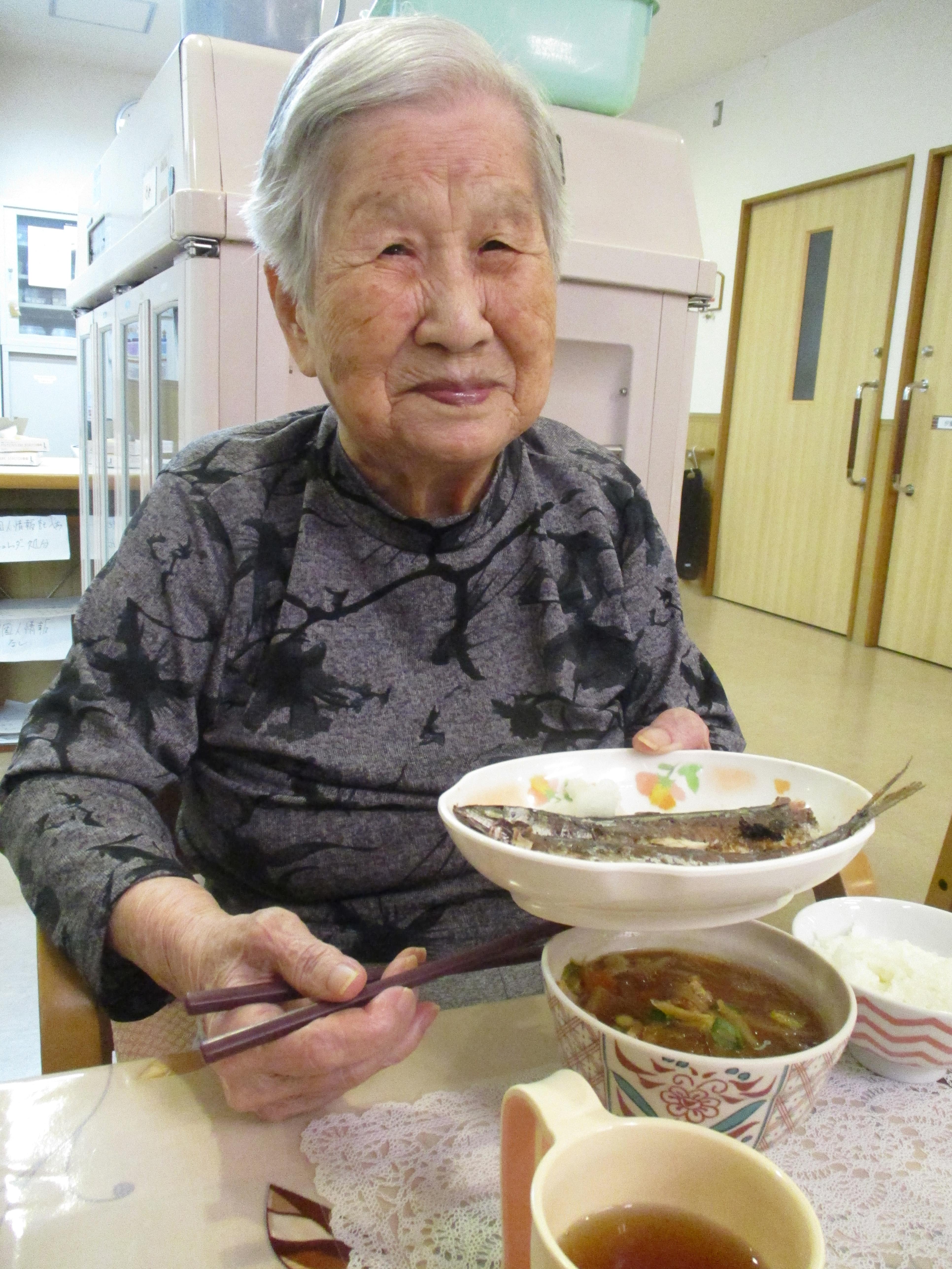 食事風景。高齢女性が食卓で食事をしている様子。介護施設の日常生活を記録した写真。